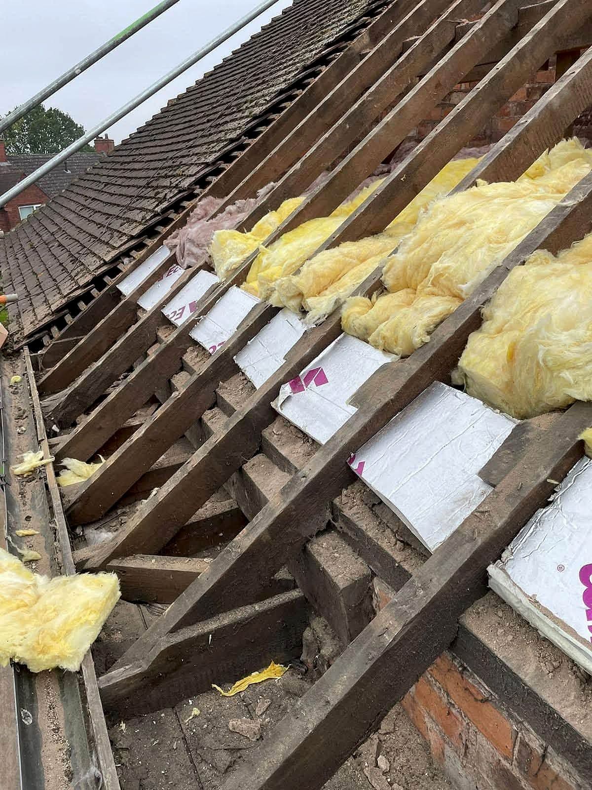 Roof stripped back to its rafters with old insulation exposed, ready for re-roofing