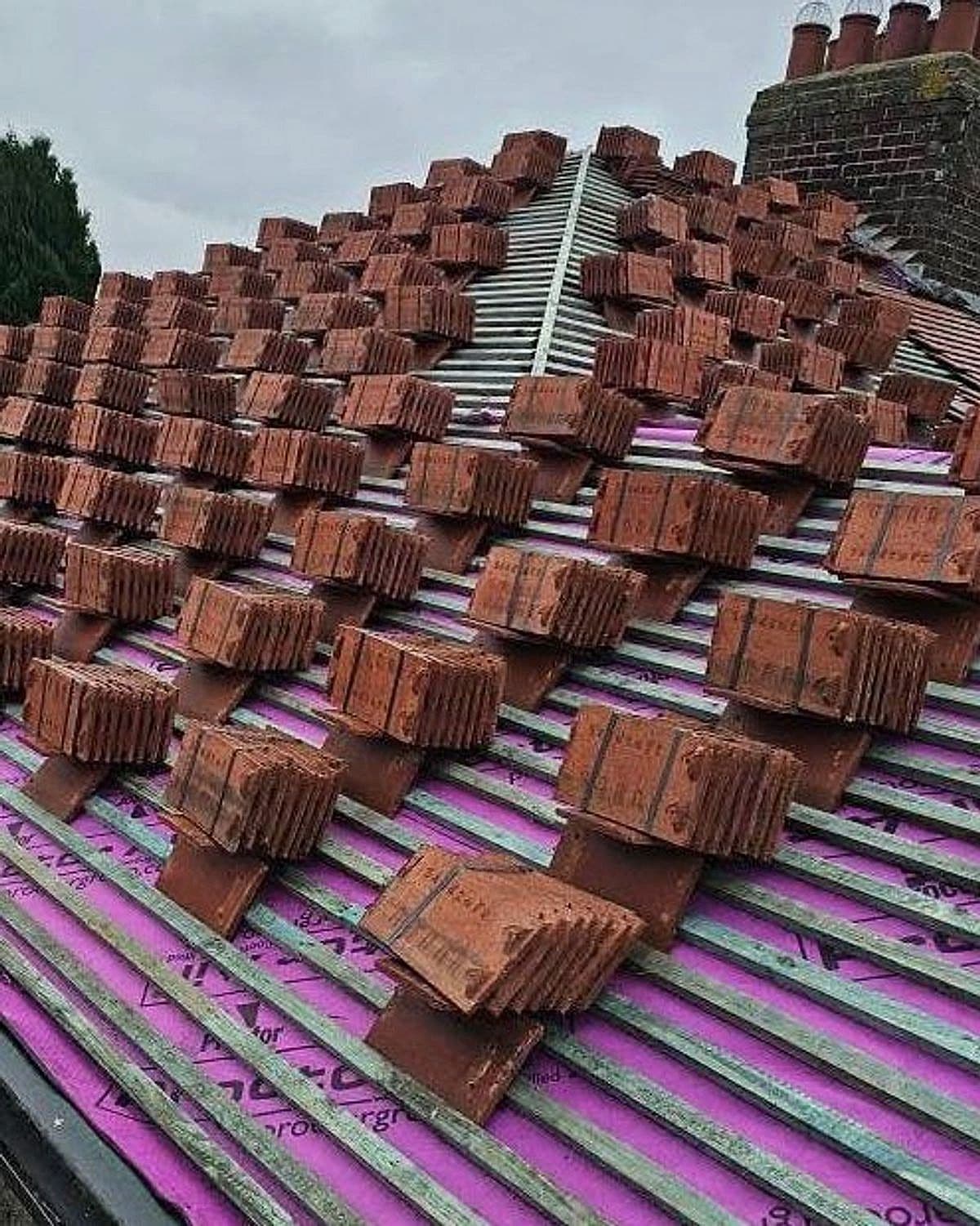 New clay roof tiles loaded out on battens and membrane ready to lay