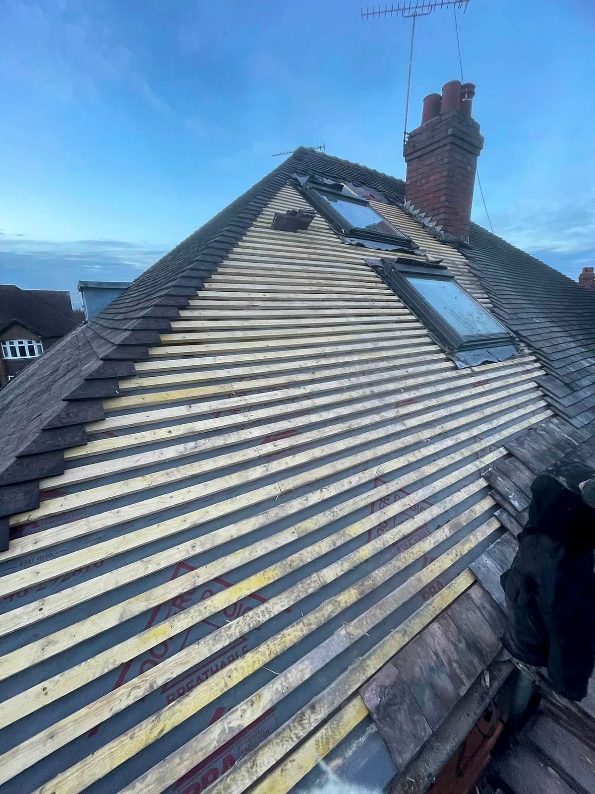 Pitched roof stripped to new battens with roof windows in place