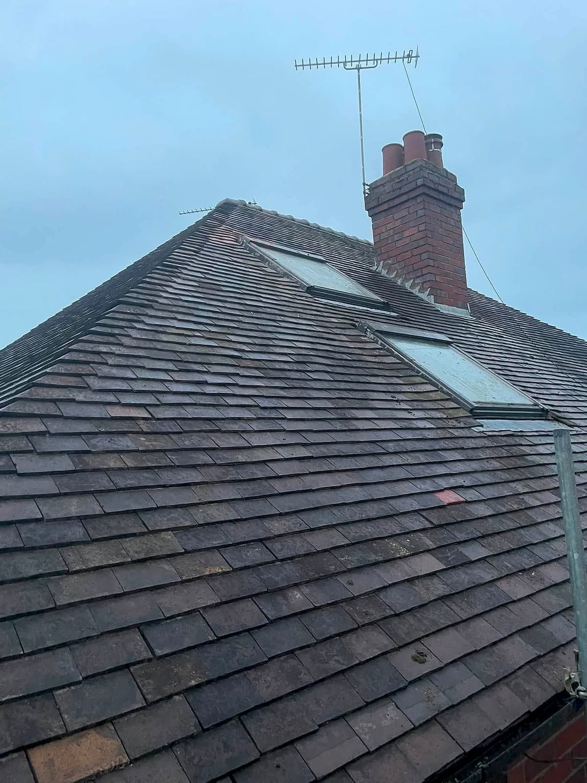 Finished tiled roof with two roof windows and a brick chimney