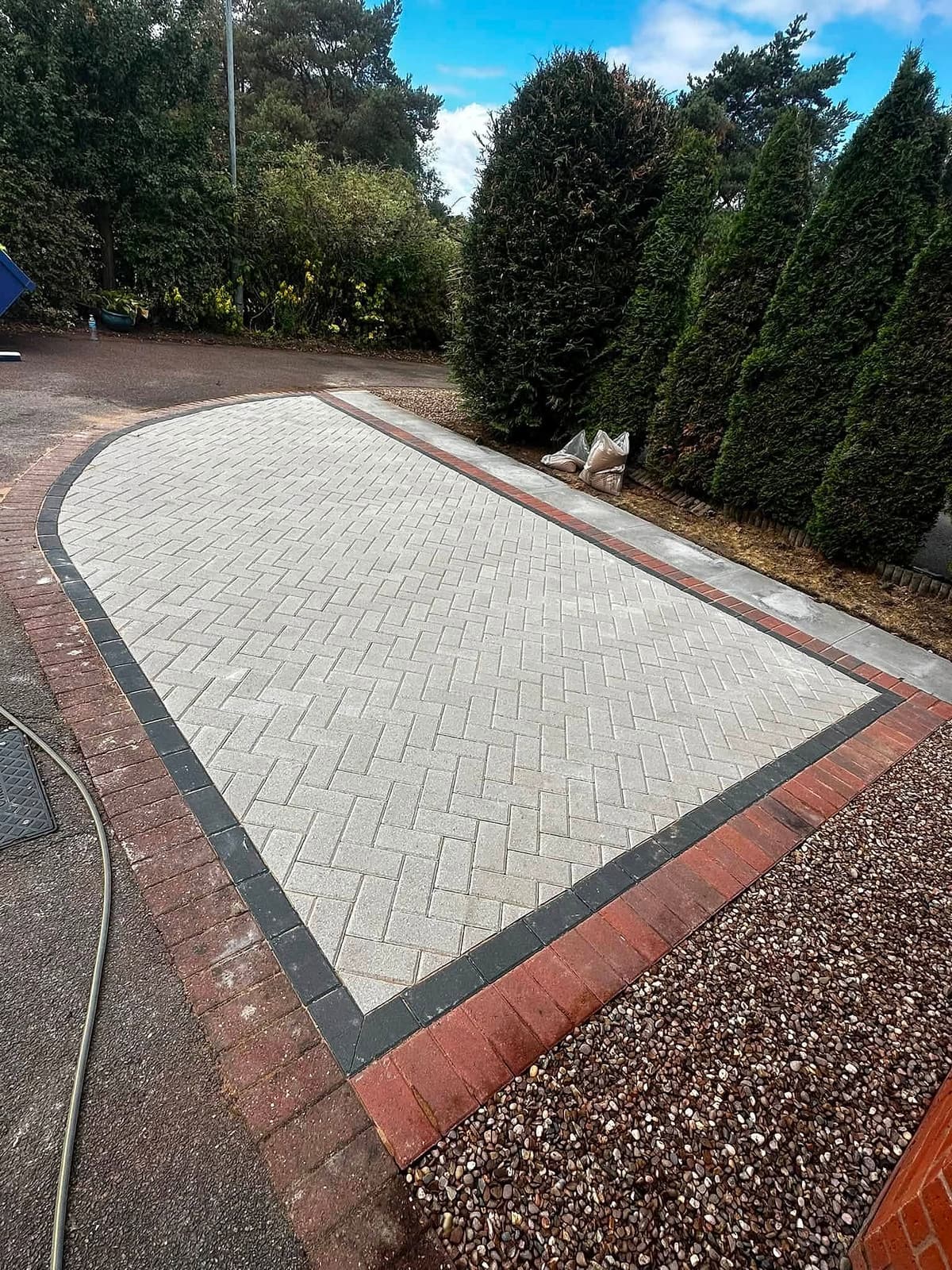 New herringbone block-paved driveway with a red brick border