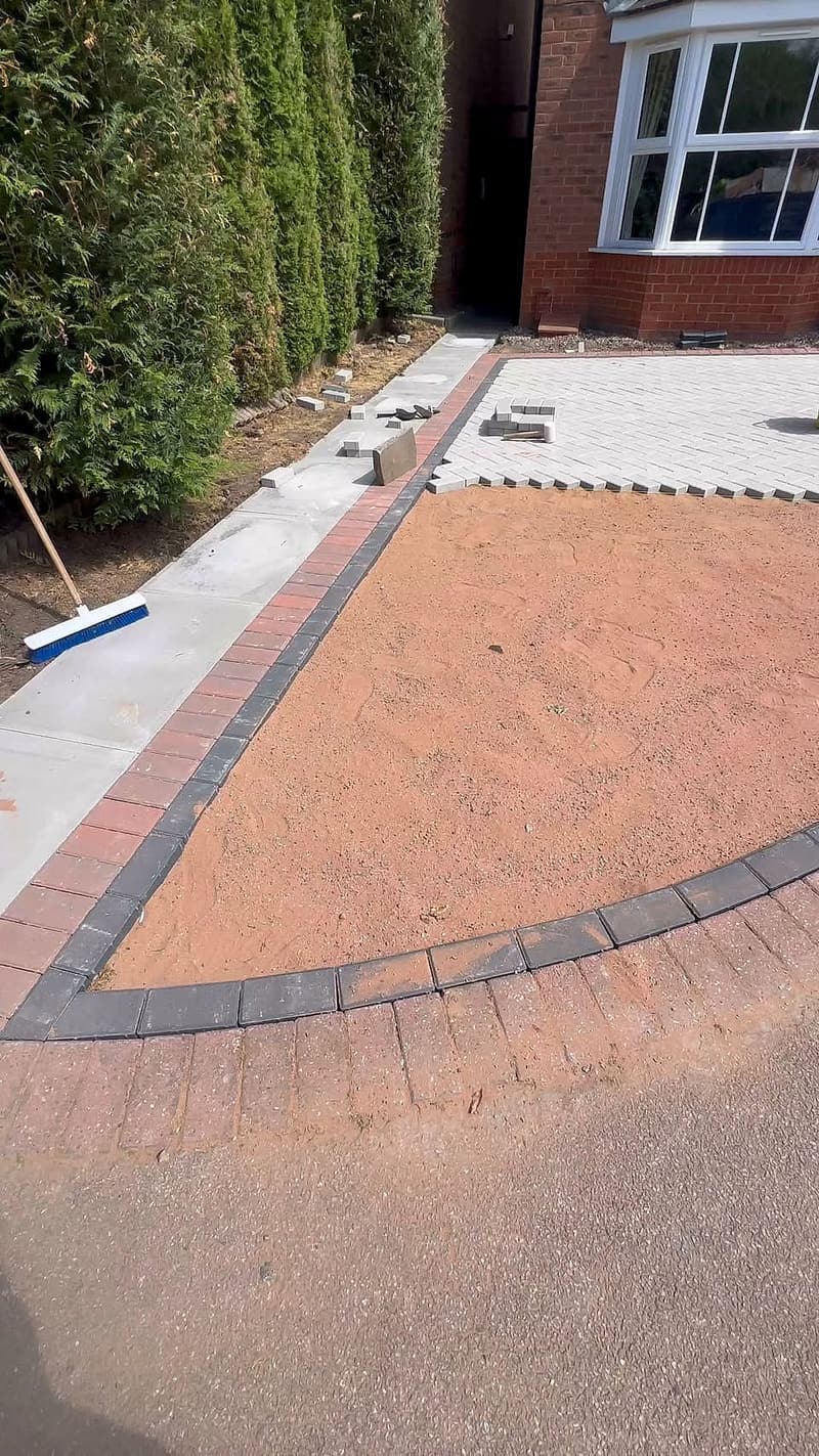 Driveway being paved with a curved block border in front of a house